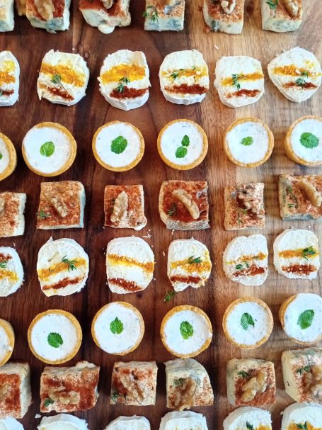 Assortiment de petites bouchées sur un plateau en bois, garnies de légumes et de sauces.