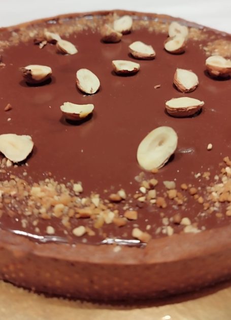 Tarte au chocolat garnie de morceaux de noisettes.