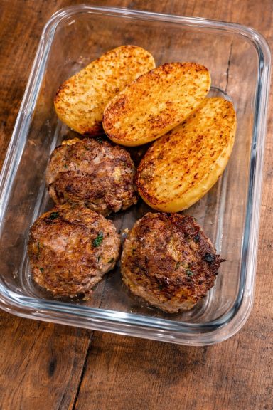 Galettes de viande et pommes de terre dorées dans un plat en verre.