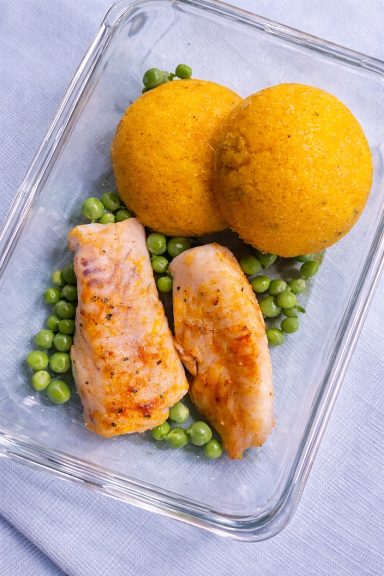 Filet de poisson grillé sur un lit de petits pois, accompagné de deux boules dorées.